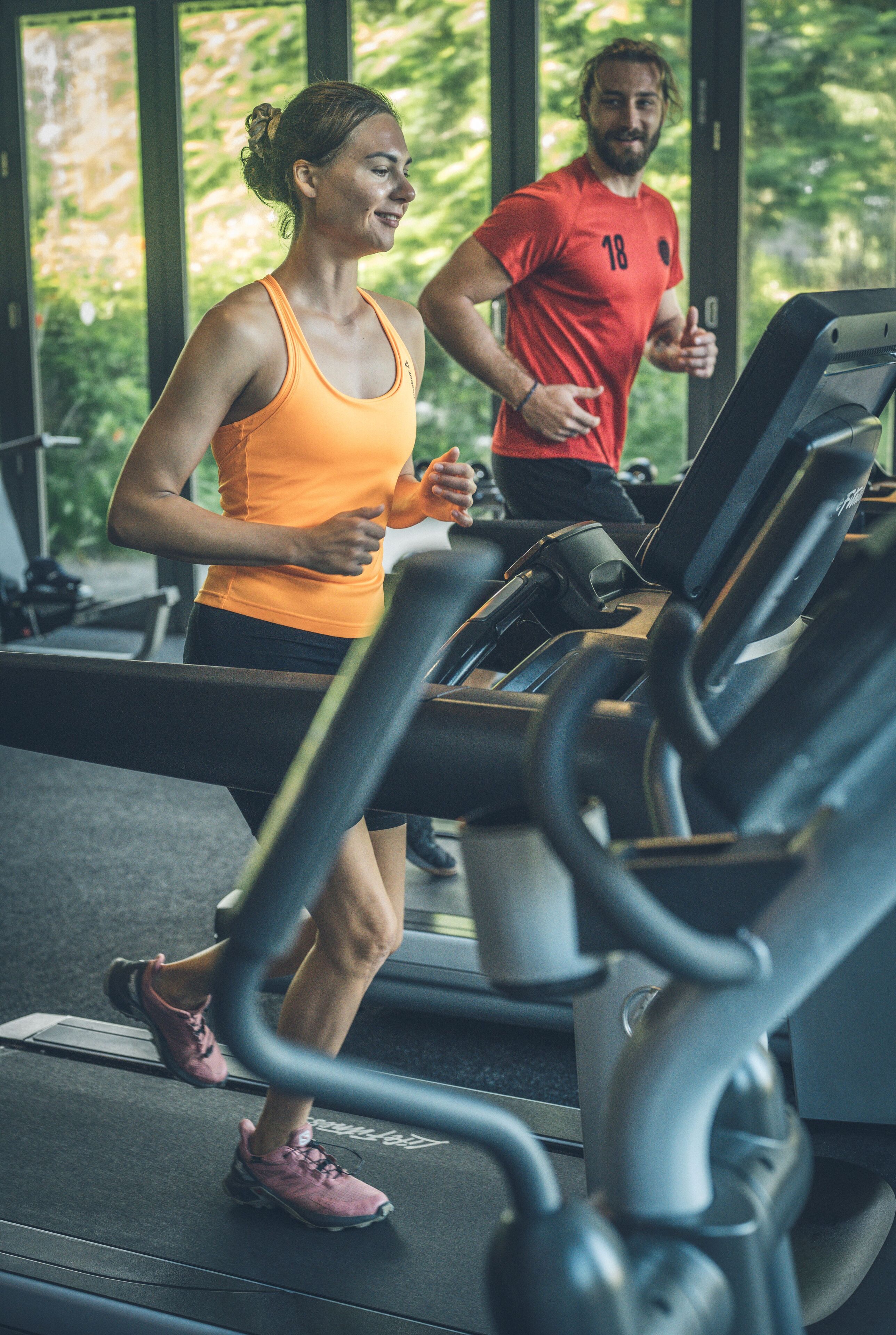 A gym with treadmills and a person running.