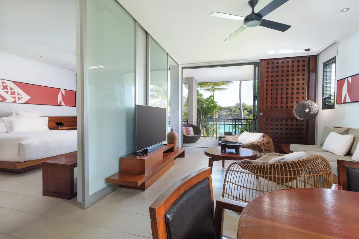 Ein modernes Hotelzimmer mit Bett, Fernseher, Sitzecke und einem Balkon mit Blick.