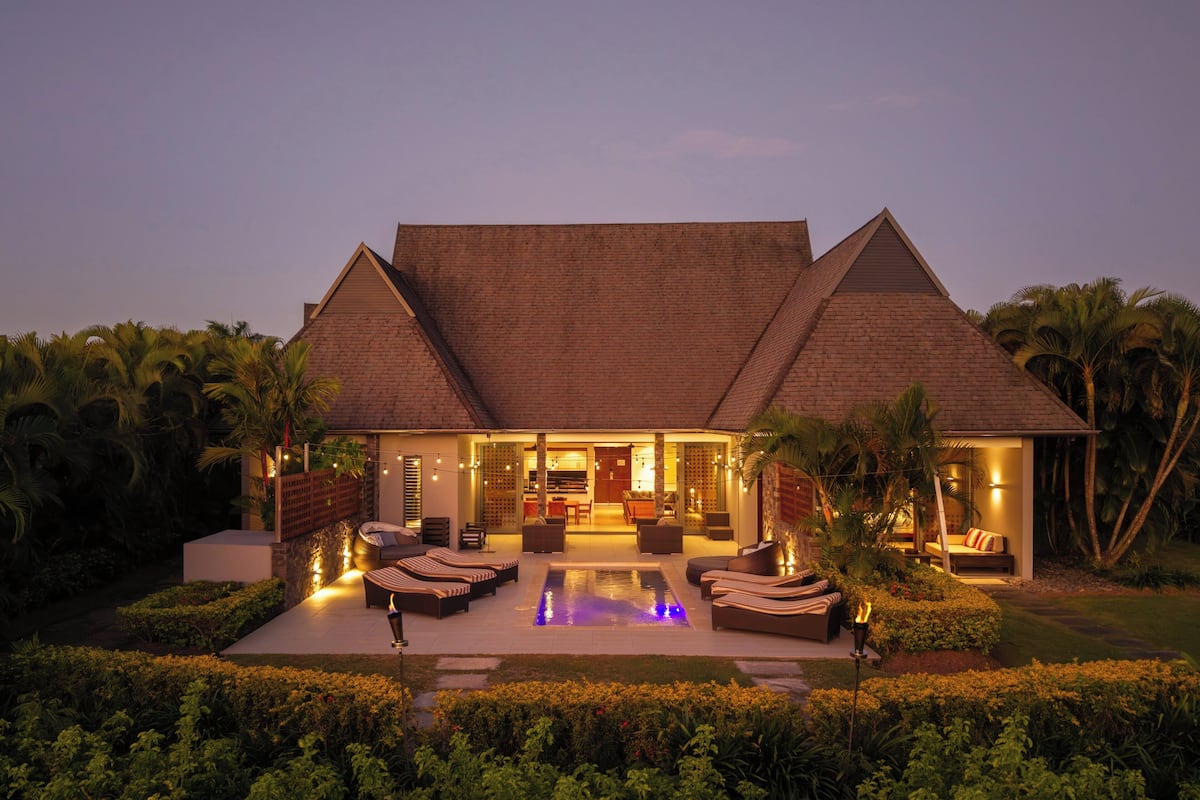 Ein Resort mit Pool, Sitzgelegenheiten im Freien und einem gut beleuchteten Eingang.