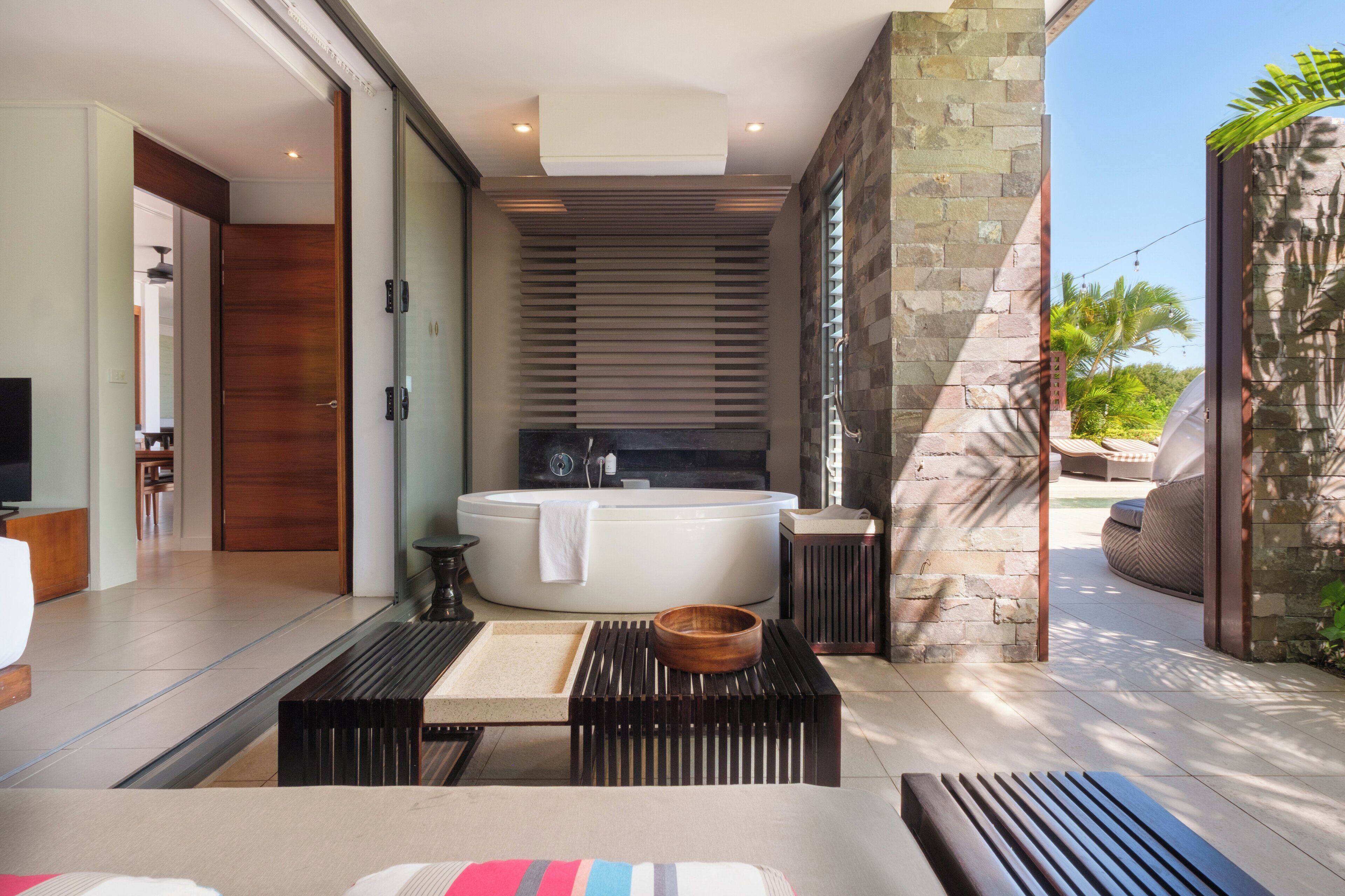 Un baño moderno con una bañera grande, un banco de madera y una mesita.