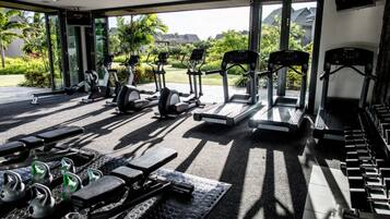Un gimnasio con diferentes equipos de ejercicio, incluyendo cintas de correr, bicicletas estáticas y pesas.