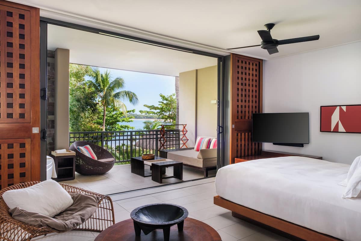 Ein Hotelzimmer mit Balkon, Bett, Fernseher und Meerblick.