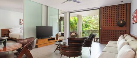 Una sala de estar moderna con un sofá, sillas, un televisor y una zona de comedor.