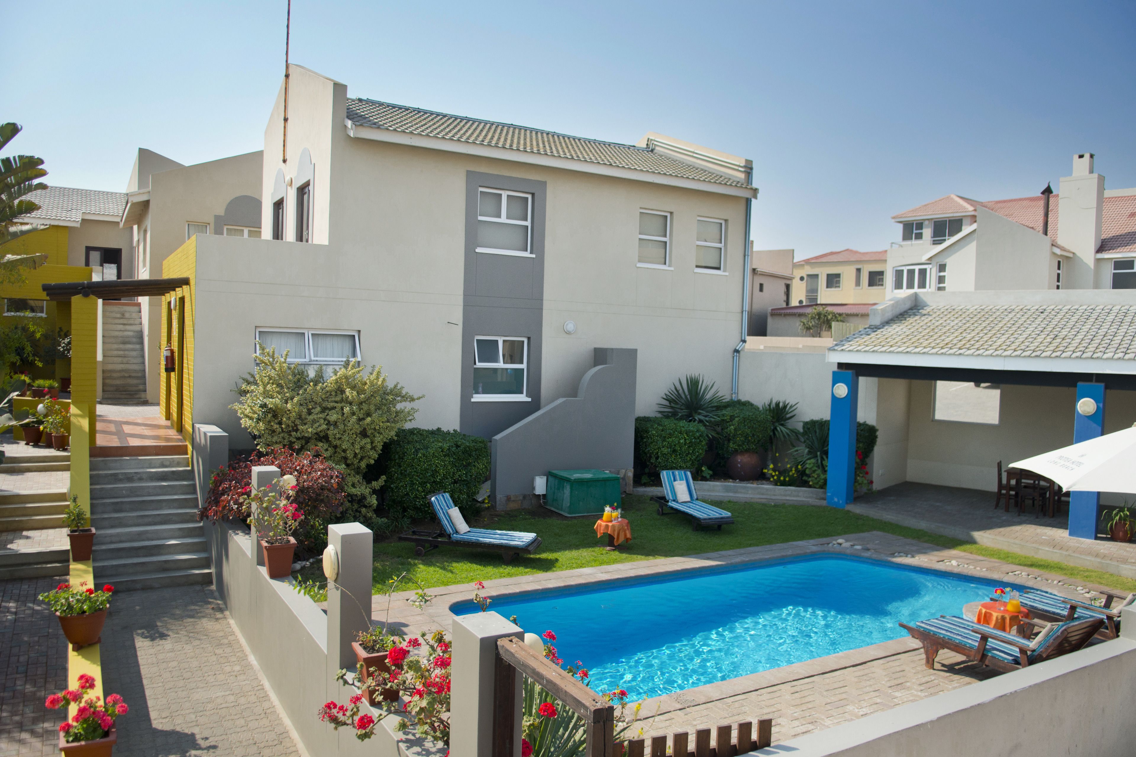 Une maison moderne dotée d’une piscine, d’un patio couvert et d’un jardin bien entretenu.