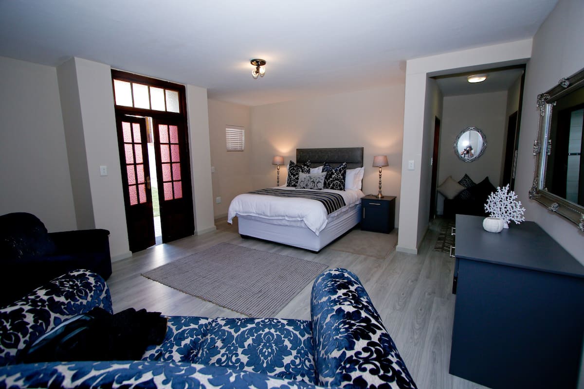A bedroom with a bed, bedside tables, a dresser, a mirror, and a door.