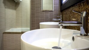 Un baño con un lavabo blanco, un grifo de cromo y un espejo sobre el lavabo.
