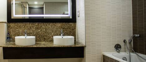 Un baño moderno con dos lavamanos, un espejo grande y una bañera.