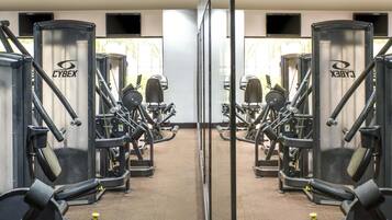 A gym with mirrored walls, exercise equipment, and a carpeted floor.