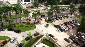 Un estacionamiento con varios coches, un área pequeña de piscina y palmeras.