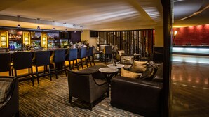 Zona de bar con asientos, barra y pantalla de televisión.