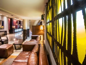 A hotel lobby with a seating area, a bar, and a patterned wall. - Mövenpick Hotel Ikoyi Lagos (Lagos)