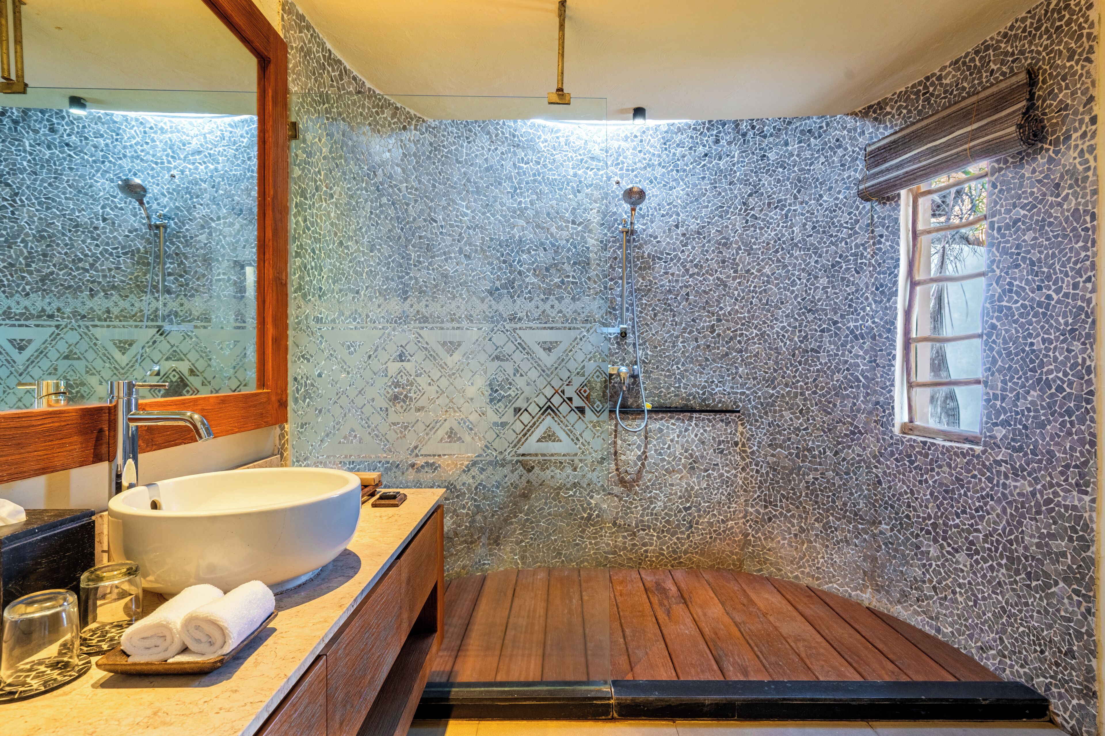 Une salle de bain avec un grand lavabo, une douche et un banc en bois.