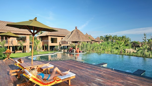 A resort with a wooden deck, lounge chairs, and a swimming pool.