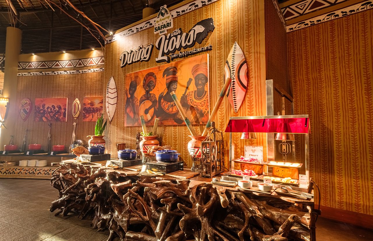 A restaurant interior with a traditional African theme, including a large mural, wooden furniture, and a buffet setup.