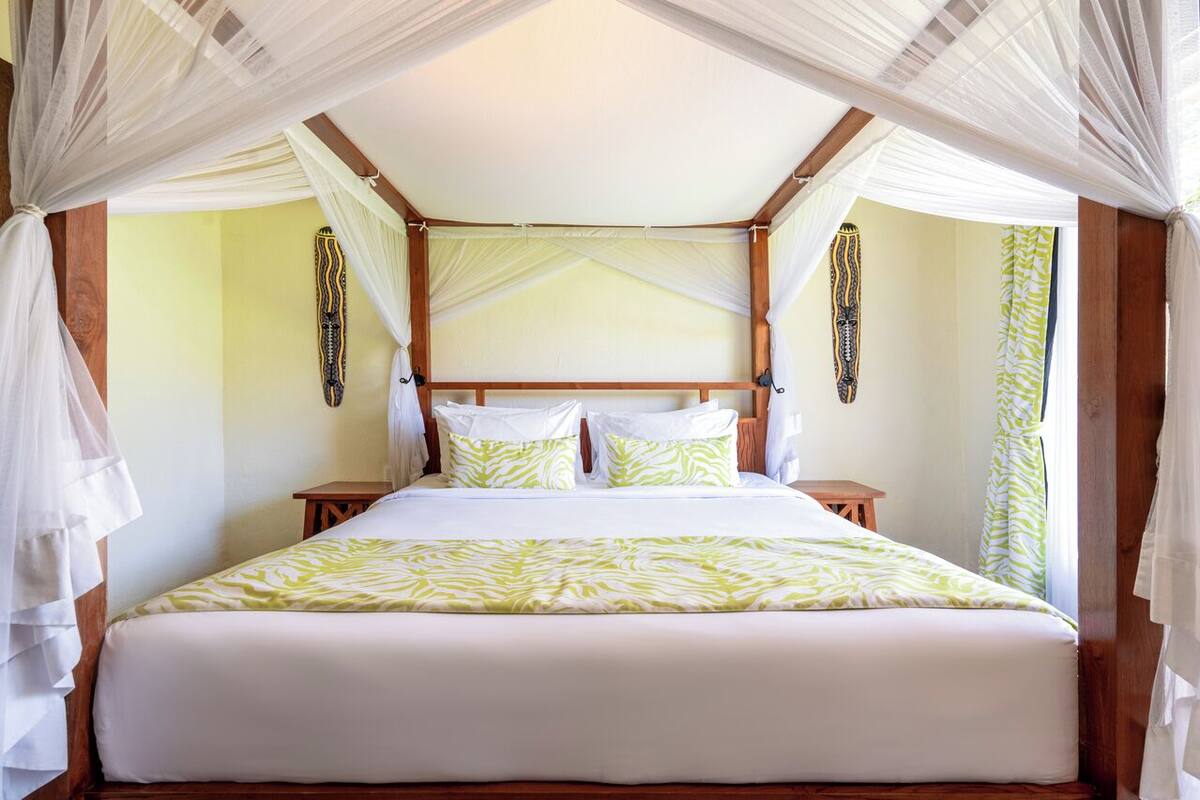 A bed with a canopy, two bedside tables, and a wall with a decorative pattern.