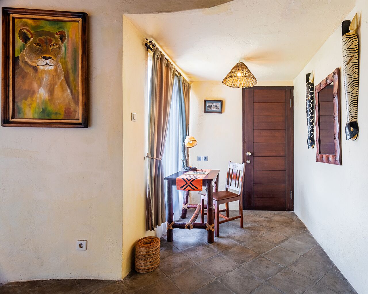 A hallway with a wooden table, chairs, a lamp, a door, and a framed painting.