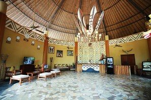 A lobby with a high ceiling, patterned walls, wooden furniture, and a reception desk. - Mara River Safari Lodge (Gianyar)