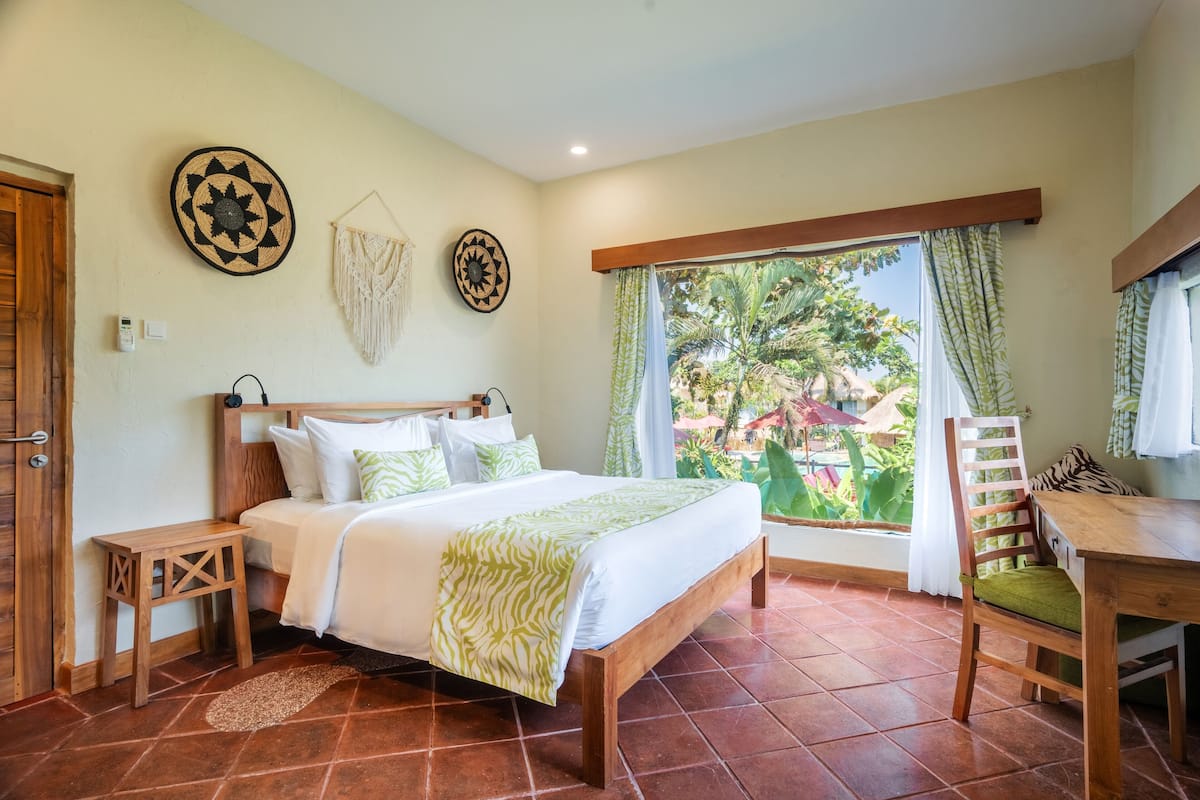 A bedroom with a bed, wooden nightstands, a desk, and a chair.