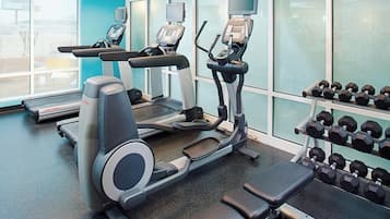 A gym with treadmills, elliptical machines, and a rack of dumbbells.