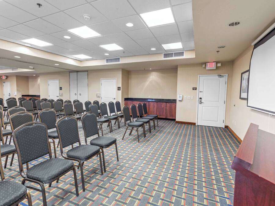 A conference room with rows of chairs, a podium, and a projector screen.