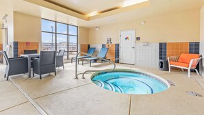 A pool area with lounge chairs, a table, and a door. - Hampton Inn Denver Northeast-Brighton (Brighton)
