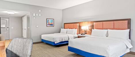 A hotel room with two beds, a desk, and a chair.