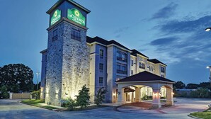 Un hôtel doté d’une tour en pierre, d’une entrée couverte et d’une façade bien éclairée.