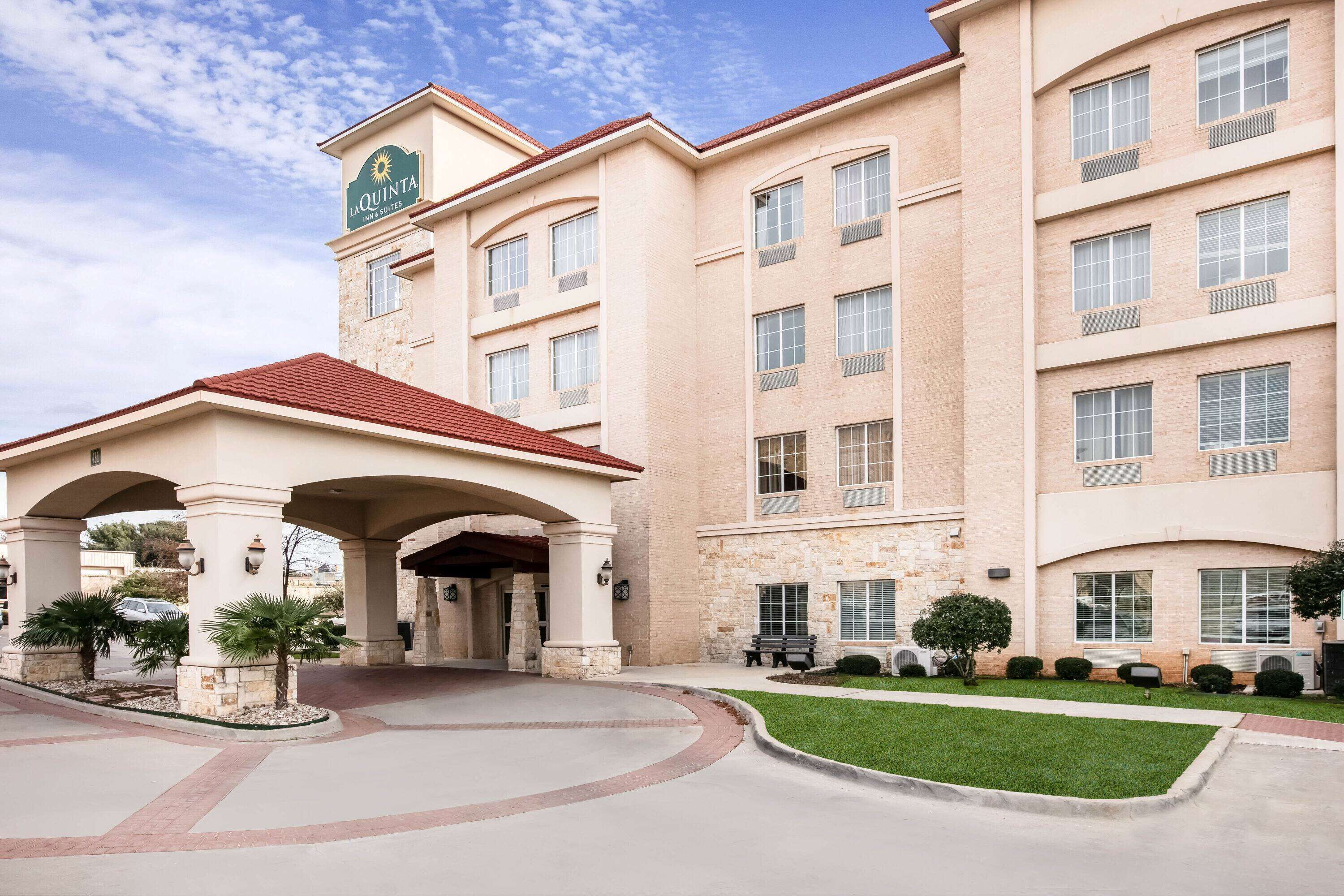 A hotel with a central entrance, multiple floors, and a clear sky.