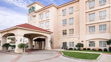 A hotel with a central entrance, multiple floors, and a clear sky.