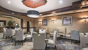 Un hall d’hôtel doté d’un tapis à motifs, de plusieurs espaces aménagés pour s’asseoir et d’un plafond en bois.
