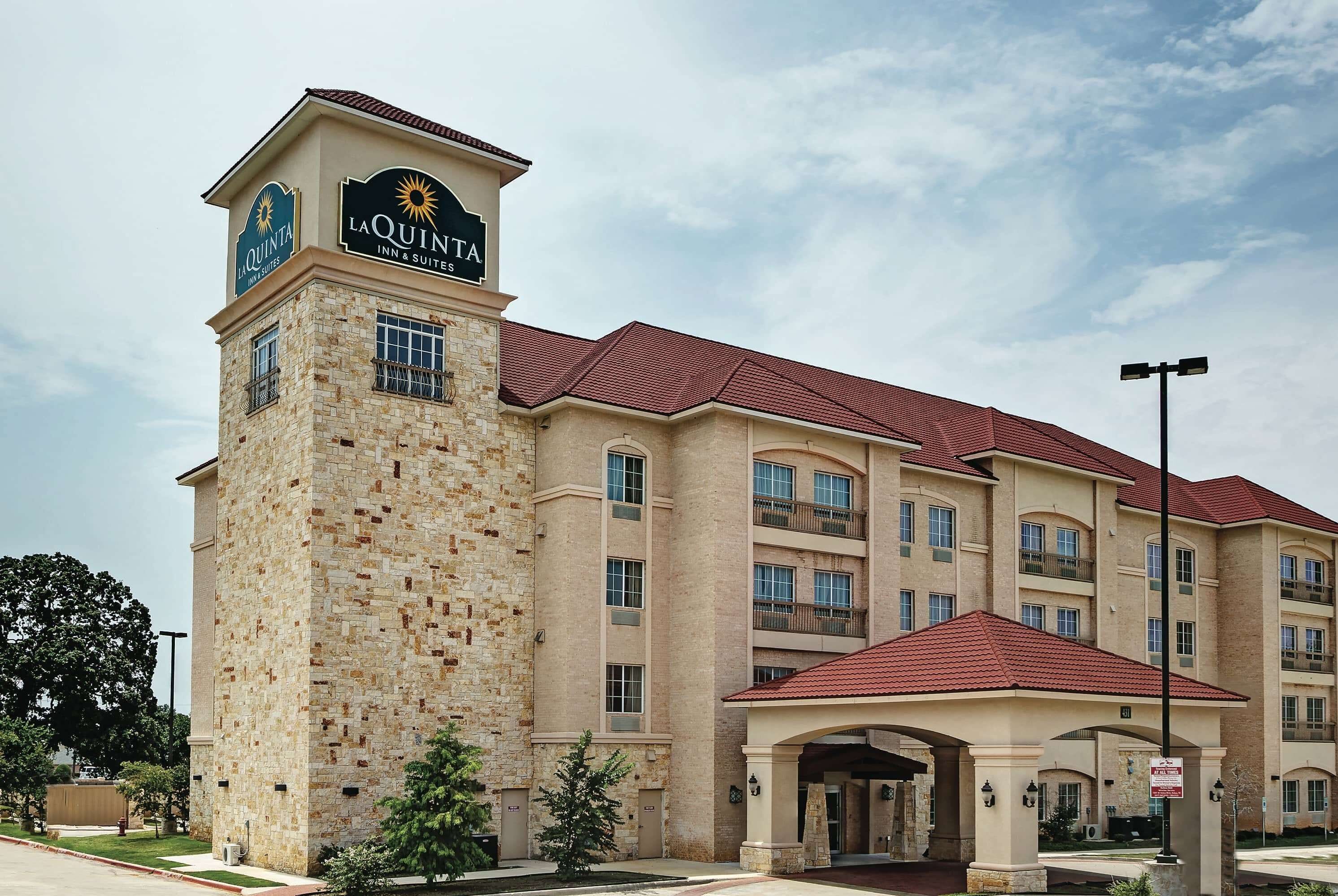 Edificio de La Quinta Inn & Suites con fachada de piedra, varios balcones y techo de tejas rojas.