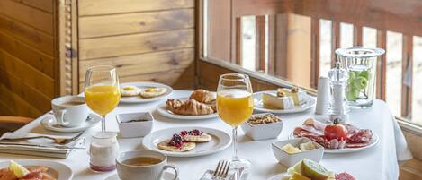 Una mesa de desayuno dispuesta con diversos platos, bebidas y utensilios.