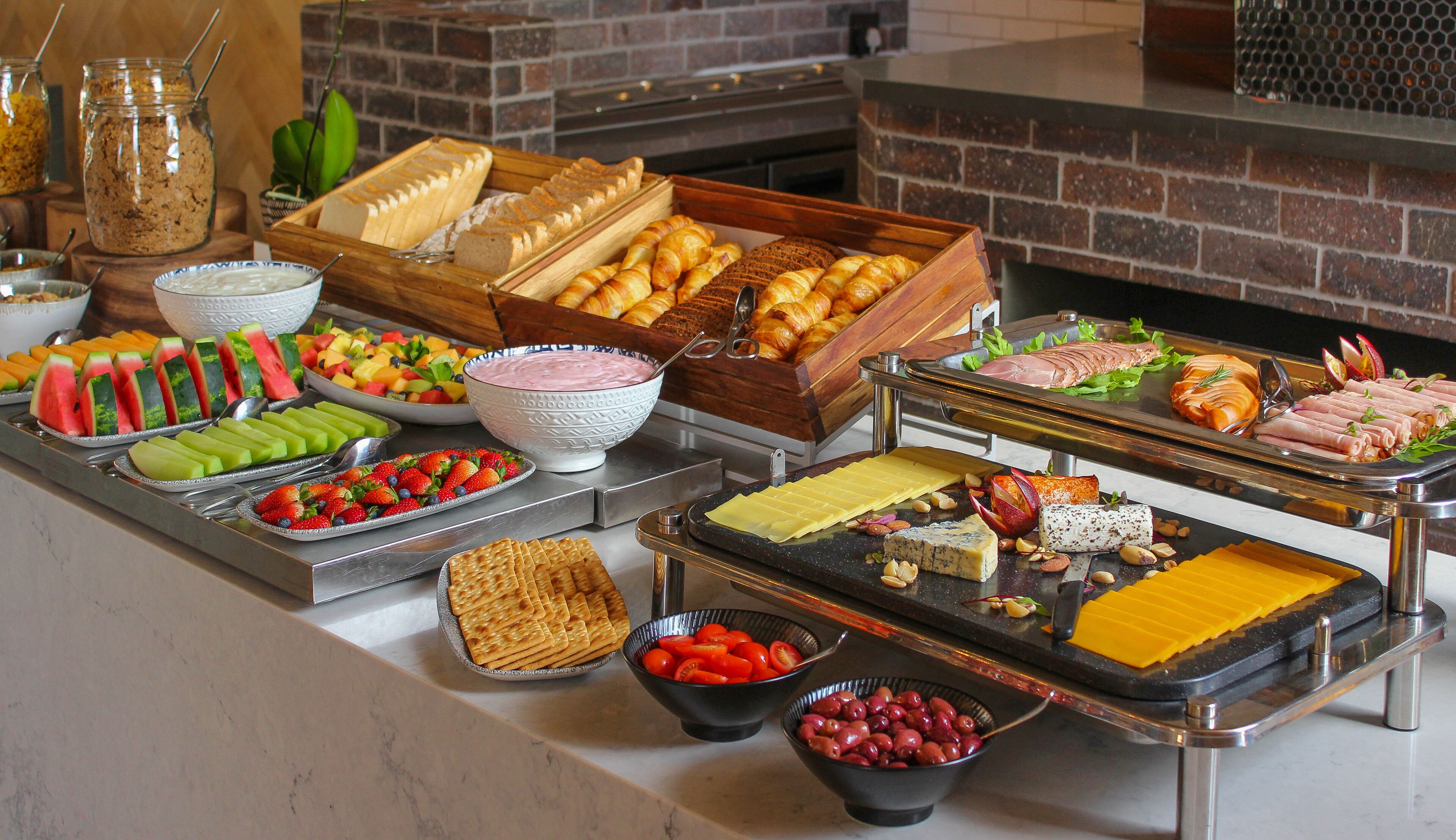 A buffet with various food items including fruits, cheeses, and meats.