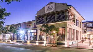 Un bâtiment moderne doté d’un toit plat, de grandes fenêtres et d’une enseigne indiquant : « The Rex Hotel ».