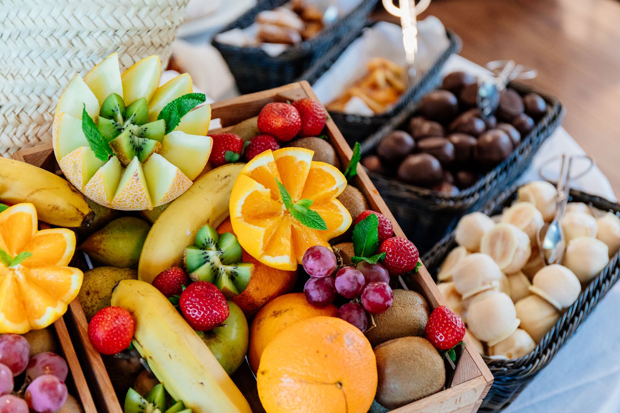 Diversas frutas y bombones expuestos en cestas de madera.