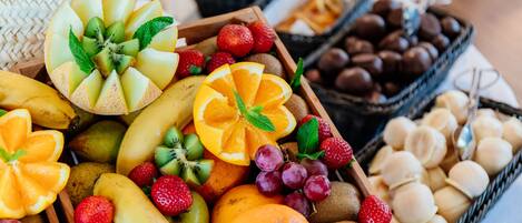 Diversas frutas y bombones expuestos en cestas de madera.