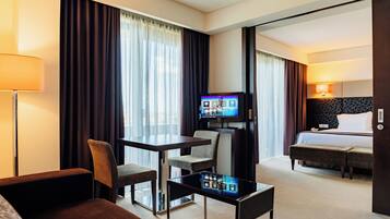 Una habitación de hotel con una cama, un escritorio con una silla, un televisor y un sofá.