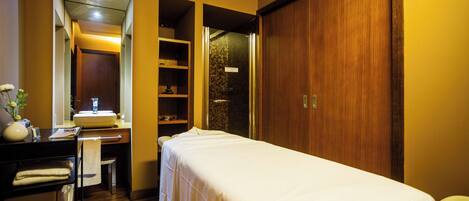 Une chambre d’hôtel comprenant un lit, une coiffeuse avec un miroir, un lavabo et une armoire en bois.