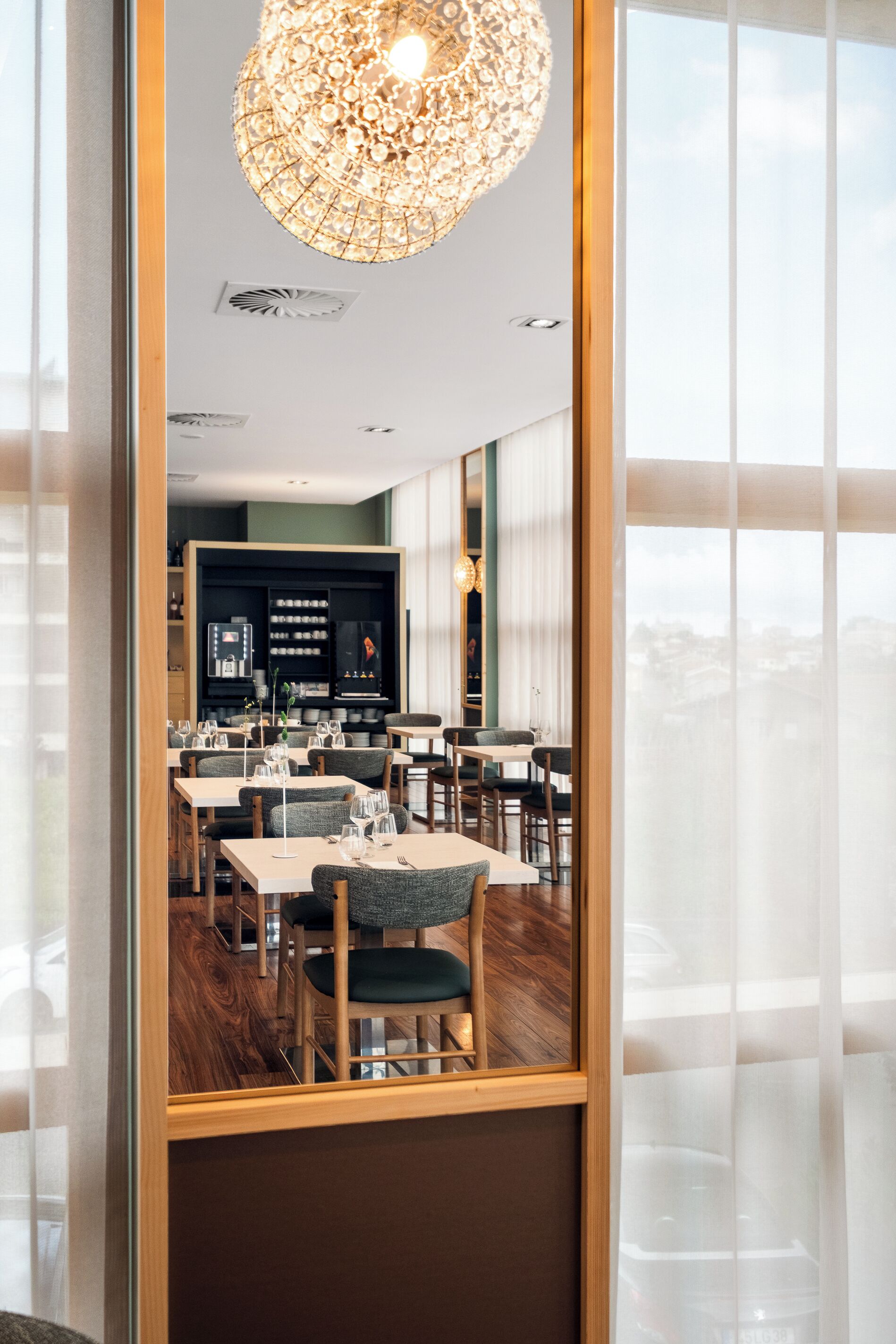 Restaurante com vista, apresentando um candelabro, mesas e cadeiras de madeira.