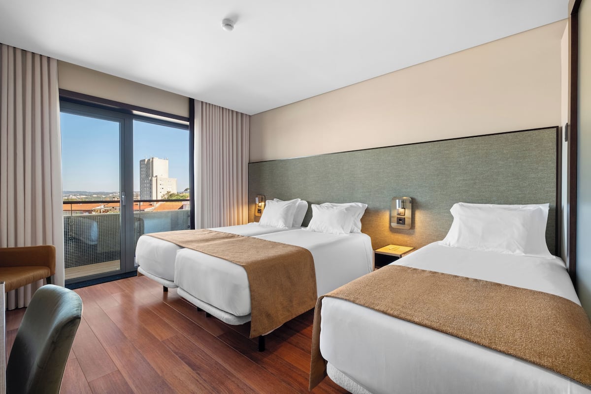 A hotel room with two beds, a desk, and a chair.