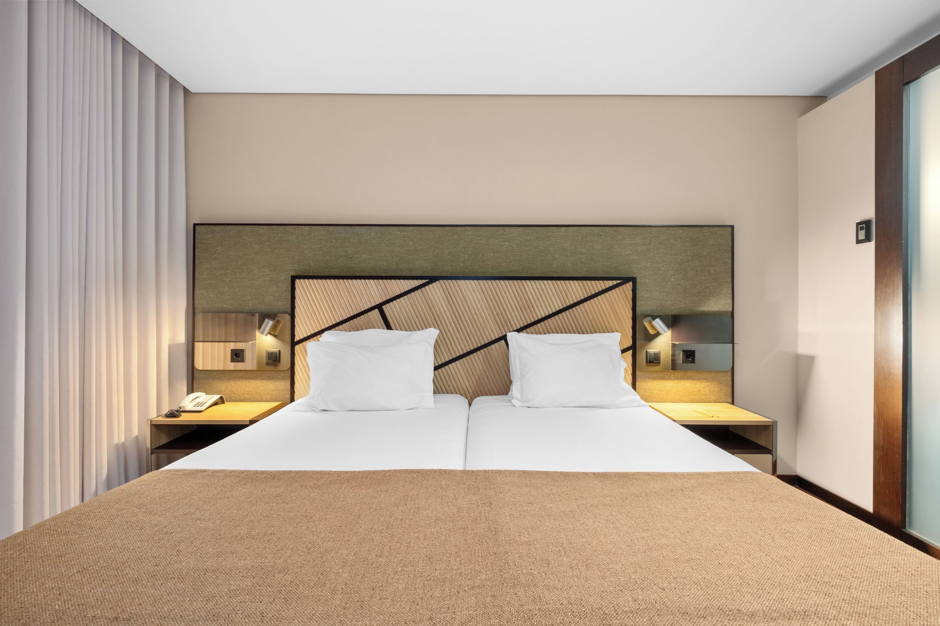 Een hotelkamer met een groot bed, twee nachtkastjes en een tv aan de muur.