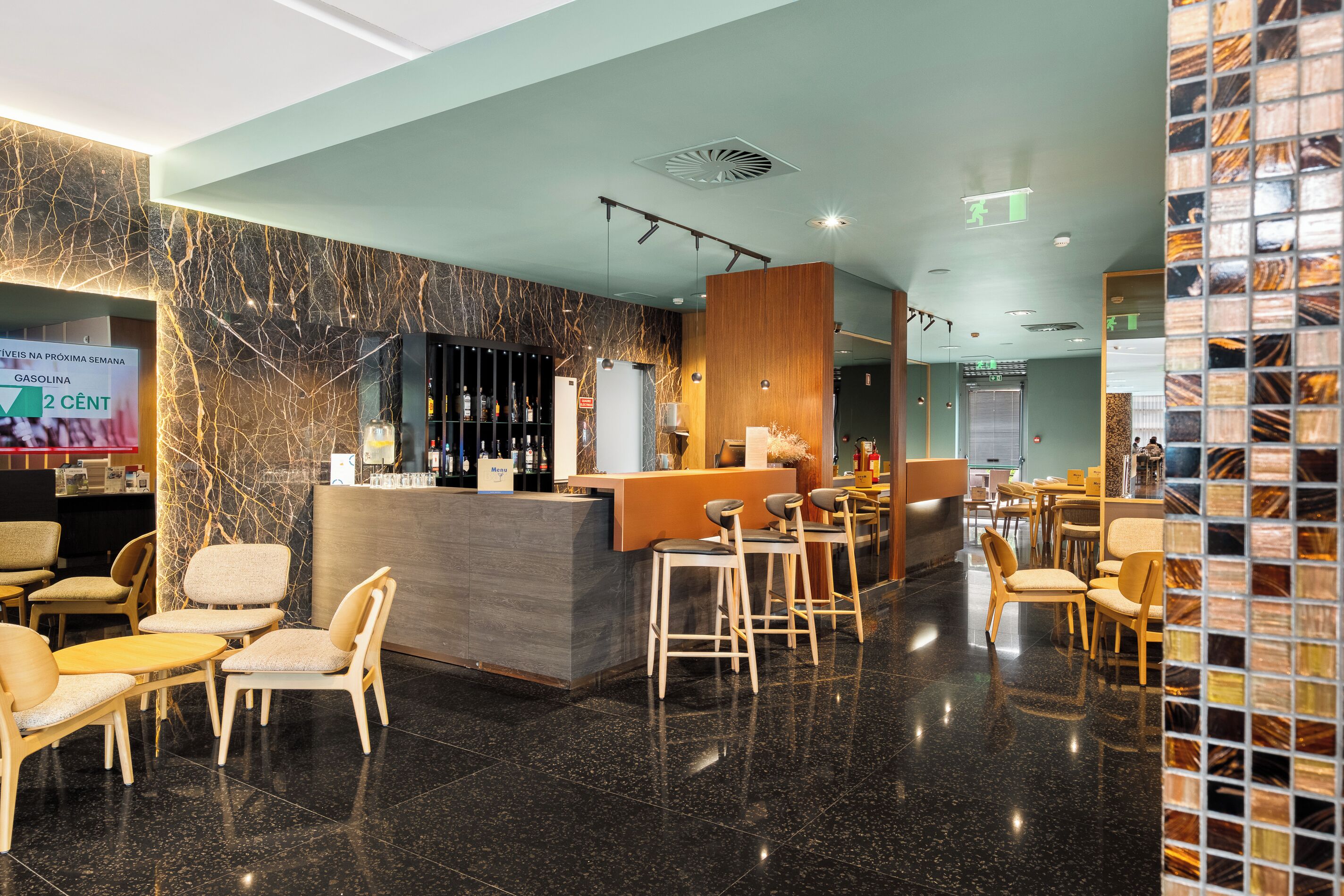 A modern bar area with a marble wall, a reception desk, and bar stools.