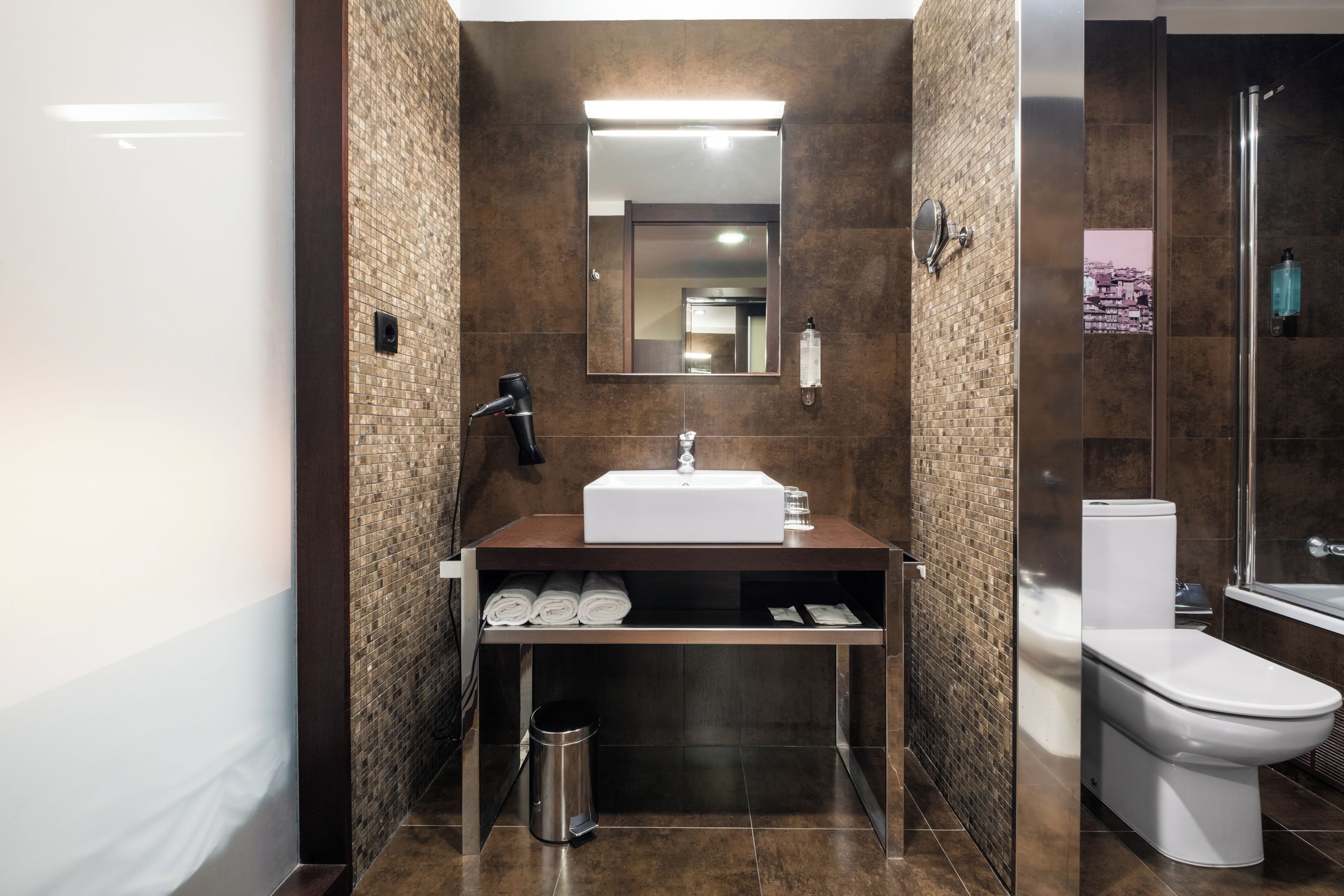 Un baño moderno con lavamanos, espejo y retrete.