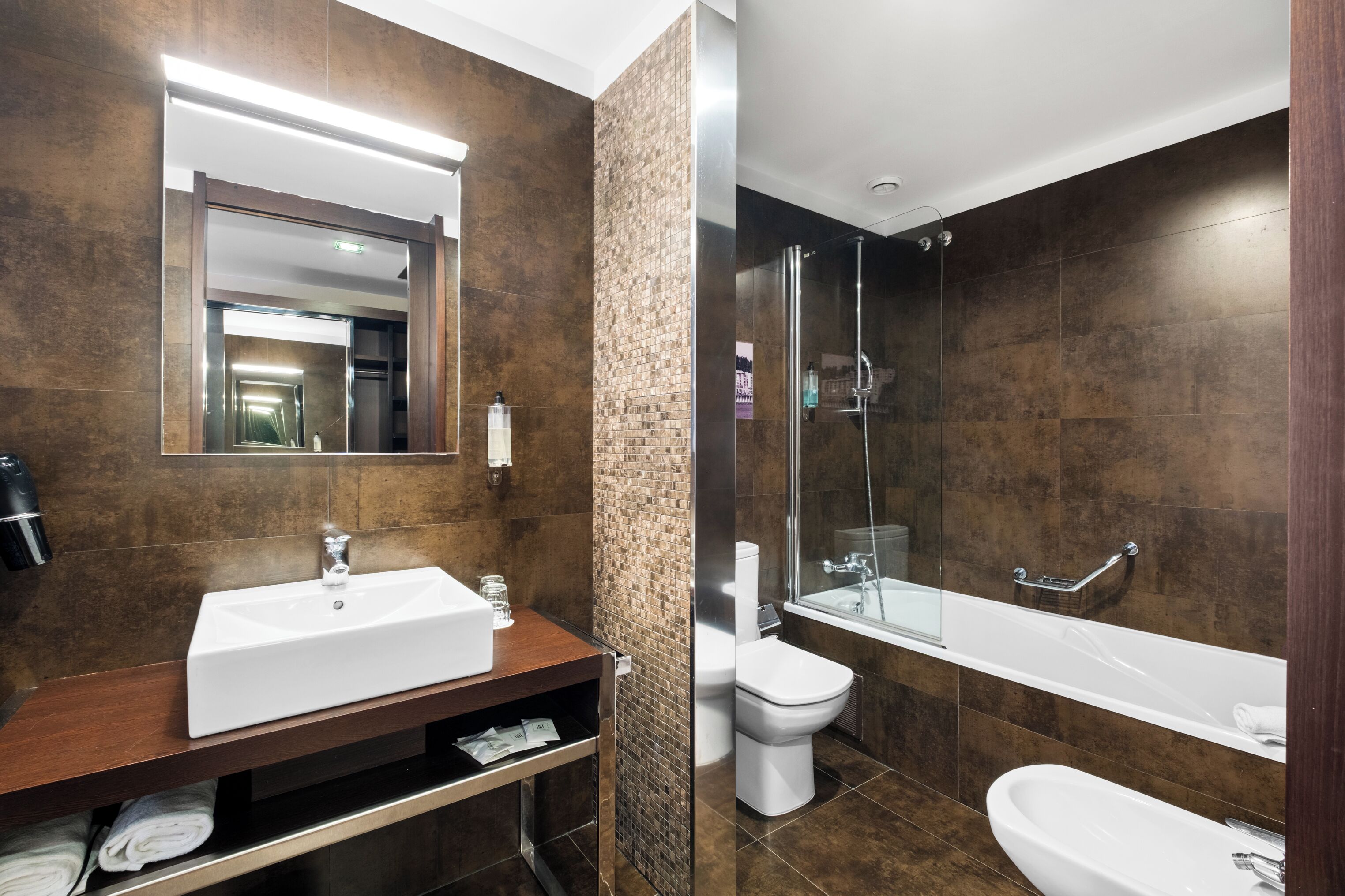Een moderne badkamer met een grote spiegel, een wastafel, toilet en een douchehoek.