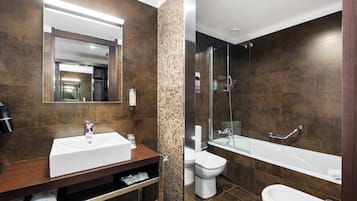 Een moderne badkamer met een grote spiegel, een wastafel, toilet en een douchehoek.