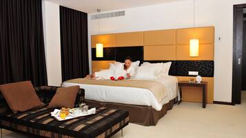 Quarto de hotel com cama, sofá e bandeja com itens de café da manhã.