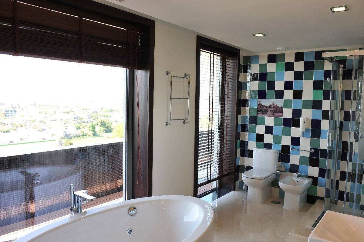 A modern bathroom with a large bathtub, two toilets, a bidet, and a shower.