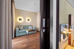 A modern room with a sofa, a small table, and a door with a keyhole. - Axis Porto Business & Spa Hotel (Matosinhos)