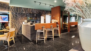 A modern bar area with a marble wall, a counter with stools, and a large vase of dried plants. - Axis Porto Business & Spa Hotel (Matosinhos)