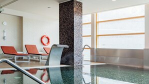 An indoor swimming pool with clear water, a tiled wall, and a lifebuoy on the wall. - Axis Porto Business & Spa Hotel (Matosinhos)